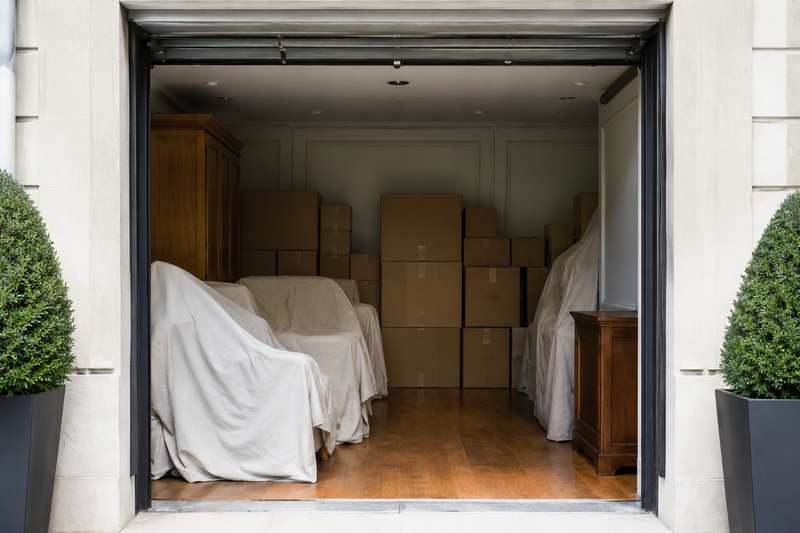 Box de stockage rempli de mobilier sous housses et de cartons empilés