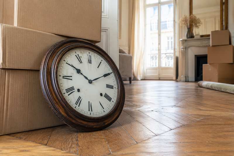 Horloge murale décrochée posée au sol contre des cartons fermés