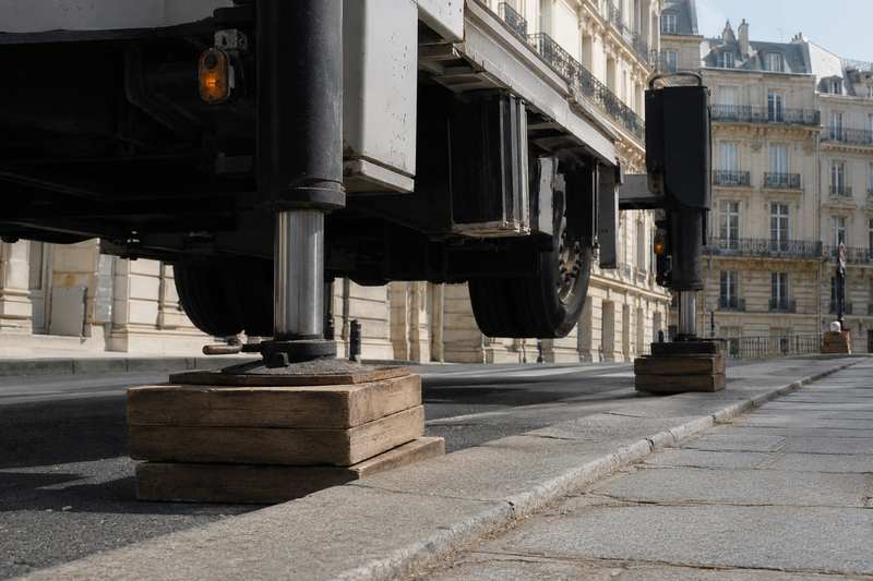 Stabilisateurs hydrauliques posés sur cales en bois au bord d'un trottoir